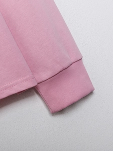 Makroansicht der Rippbündchen und des Doppelnaht-Saums des rosa gestrickten T-Shirts