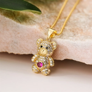 Macro shot of gold teddy bear necklace with pink crystal and white zircon pavé