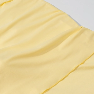Détail du tissu en maille jaune montrant une texture lisse et une couture fine