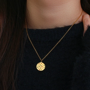 Gold pendant necklace with colorful cubic zirconia crystals on a black sweater