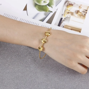 Golden stainless steel bracelet with three flat round beads worn by a female hand model