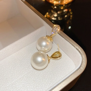 Detail of elegant gold-plated drop earrings with oval pearl and sparkling zircon stone