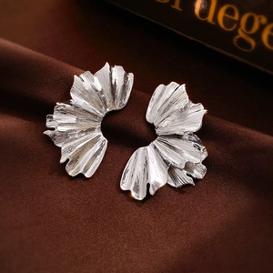 Vue détaillée des boucles d'oreilles en métal plissé argenté sur velours foncé