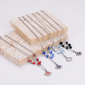 Set of four stainless steel evil eye necklaces in red, blue, and black on travertine