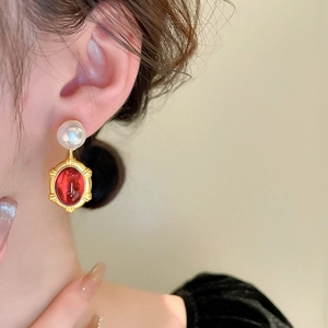 Detail of vintage French style pearl and oval red resin drop earrings worn by model