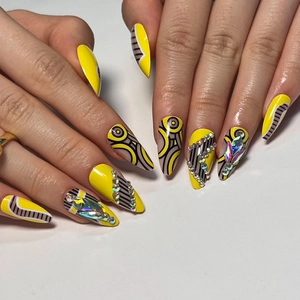 Creative stiletto press-on nails with bright yellow base, black stripes and colorful rhinestones