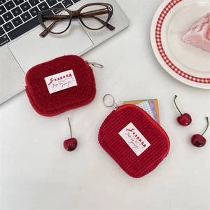 Red plush corduroy small square wallet for coins and earphones on a white desk