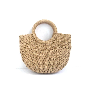 Close-up of woven straw texture and circular top handles on the semi-circular tote bag