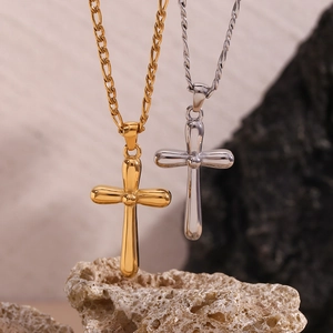 Polished gold and silver 3D cross pendants on Figaro chains over natural rock
