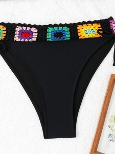 Detail of black bikini bottoms featuring colorful crochet granny square waistband trim