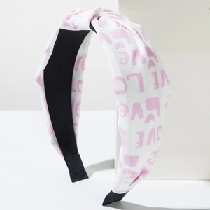 Close-up of knotted pink and white headband with LOVE print and heart patterns