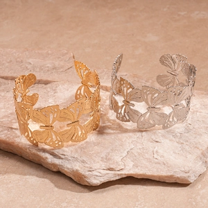 Elegant gold and silver open butterfly bracelets on a natural stone base