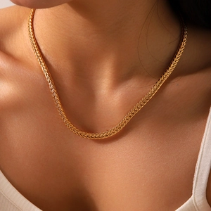 Close-up of a detailed 18K gold braided wheat chain necklace with premium metallic luster