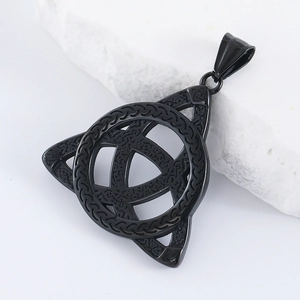 Détail macro du pendentif noir nœud celtique sur pierre blanche montrant la texture métal