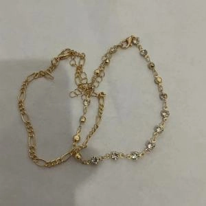 Close-up of golden Figaro chain and rhinestone link anklets with adjustable lobster clasps