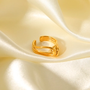 Macro view of gold-plated multi-layer twisted ring on champagne silk fabric background