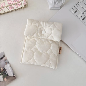 Macro shot of white quilted heart pattern sanitary bag with snap button on a desk