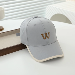 Detail of grey kids baseball cap featuring brown W embroidery and beige brim piping