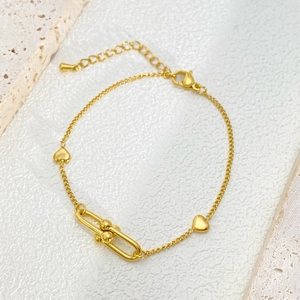 Detailed close-up of gold U-shaped link bracelet with polished heart charms and adjustable clasp