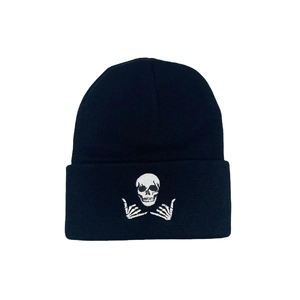 Close-up of skull and skeletal hands white embroidery on a black ribbed knit beanie