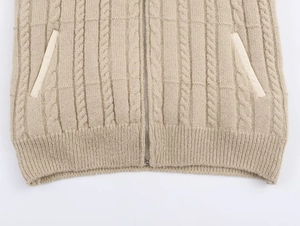 Detail of cable knit pattern and metal zipper on beige padded sweater vest