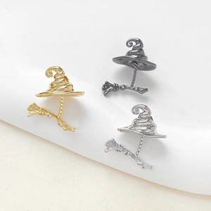 Macro detail of witch hat and broom pendants with cubic zirconia in gold, silver and black