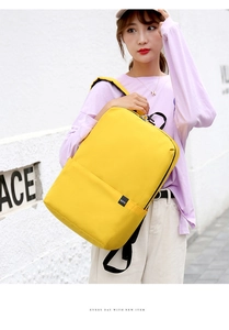 Detail of a bright yellow nylon backpack featuring a woven label and black handle