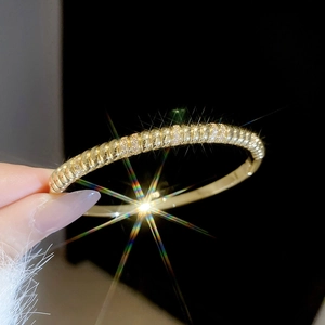Macro shot of gold-plated twisted cuff bracelet with white zircon inlay on hand