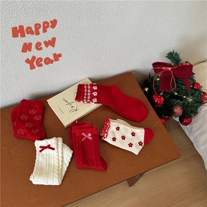 Flat lay of five pairs of red and white festive socks with holiday patterns on wood