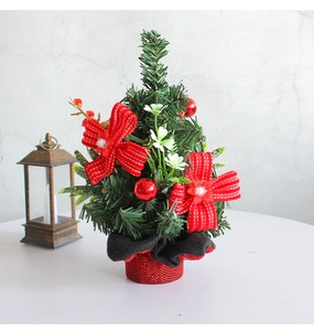 Detailed view of mini Christmas pine tree with red bows and festive cloth base on a table