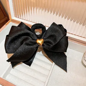 Pince à cheveux élégante en satin noir avec boucle cœur dorée dans une boîte à bijoux