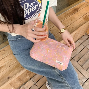 Close-up of pink quilted makeup bag with floral embroidery and brand woven label detail