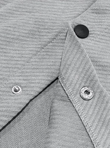 Macro view of metallic snap buttons and ribbed knit texture on grey jacket detail