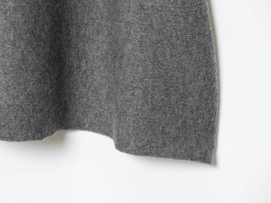 Close-up of the grey knitted dress hem showing fine fabric texture and premium stitching