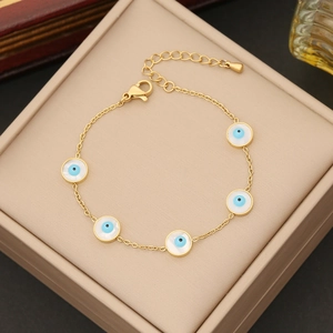 Gold evil eye jewelry set with five blue charms and adjustable lobster clasp on a beige box