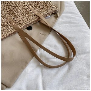 Detail of woven cutout pattern and brown leather handle on a khaki commute tote bag