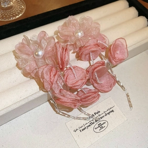 Detail of pink mesh flower earring with pearl center and long beaded tassel on velvet tray