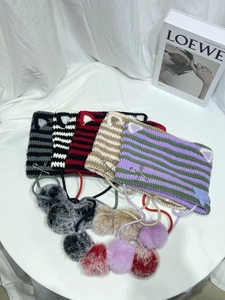 Detail of colorful striped cat ear knit beanies with plush pom-poms and silver pins