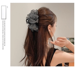 Détail d'une grande pince à cheveux en dentelle noire avec perles sur coiffure élégante