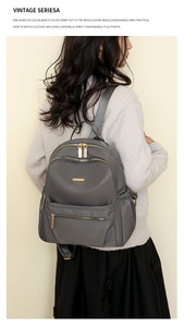 Detail of grey nylon backpack with gold double zippers and texture on a model