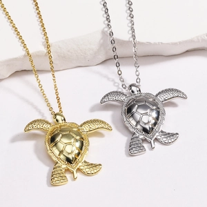 Detail of gold and silver sea turtle necklaces with textured shell on white stone