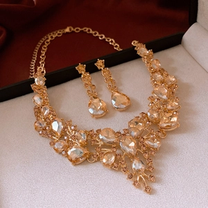 Gros plan d'un ensemble de bijoux dorés avec cristaux champagne sur fond de soie rouge