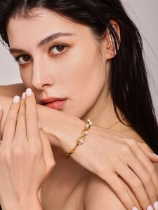 Close-up of 18K gold plated C-shaped bangle with elegant white pearls on a model wrist