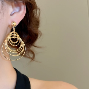 Side view of multi-layer golden circle earrings on model for a high-end luxury look