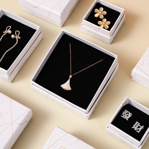 Flat lay of marble pattern jewelry boxes with fan pendant necklace and creative earrings