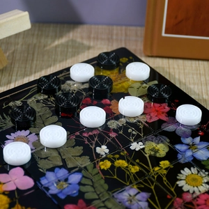 Détail d'un échiquier en résine avec fleurs séchées et pions de jeu noirs et blancs
