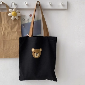 Detail of black canvas tote bag with a cute brown bear print and khaki woven handles