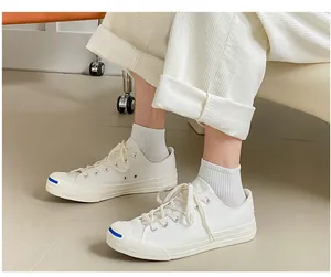 Detail of white Jack Purcell canvas sneakers with blue smile toe cap and cotton socks