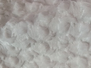 Macro detail of white plush heart pillowcase showing soft dotted texture and fabric weave
