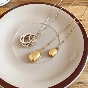 Detail of 18k gold plated water drop pendant and interlocking triple ring necklace